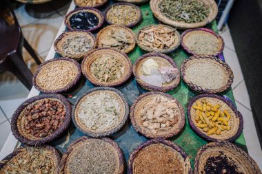Agadir, Morocco - February 25, 2024 - Baskets filled with various herbs and spices displayed on a table. clipart