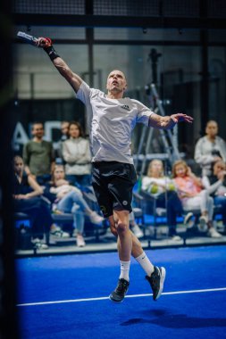 Riga, Letonya - 3 Mart 2024 - Bir oyuncu arka planda seyircilerle yüksek bir topa vurmak için zıplıyor.