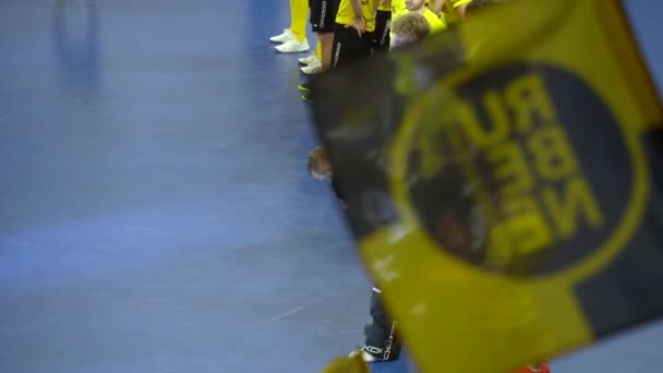 2024年3月10日 ラトビアのヴィラエラ 黄色いジャージと黒いショートパンツのアスリートは 青いスポーツコートのラインに注意深く立って 部分的に黄色と黒の旗に取り付けられています — ストック動画