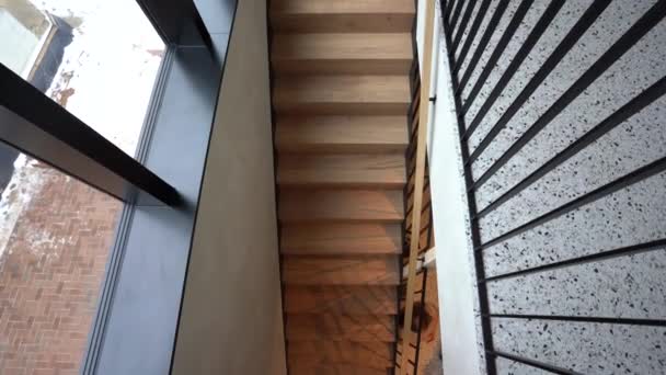 从上往下俯瞰的现代楼梯 有木制台阶 黑色金属栏杆和梯形地板 通往入口 — 图库视频影像