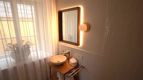 拉脱维亚塞西 2024年2月14日 一间明亮的浴室 有木制镜框 木制看台上有一个圆形的水盆 墙面浮雕 瓷砖墙 透明的窗帘 以及窗外有花的窗户 — 图库视频影像