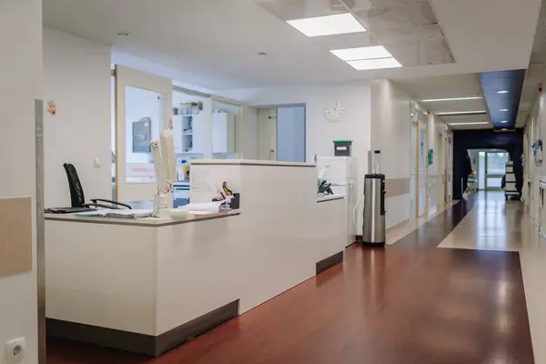 Valmiera, Letonya - 20 Mart 2024 - Bir hemşire masası, sandalye, bilgisayar ve çeşitli ofis malzemelerinin bulunduğu hastane koridoru, tıbbi afişlerin yanı sıra.