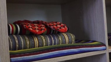 Katlanmış renkli battaniyeler ve bir çift eldiven ahşap bir rafa düzgünce yerleştirilir..