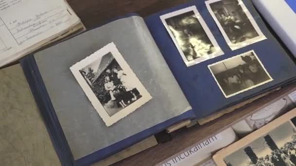 インキュカルンズ ラトビア 2024年3月10日 青いページに黒と白の写真を含むオープンヴィンテージのフォトアルバム 他の文書と一緒に木製のテーブルの上に眠る — ストック動画