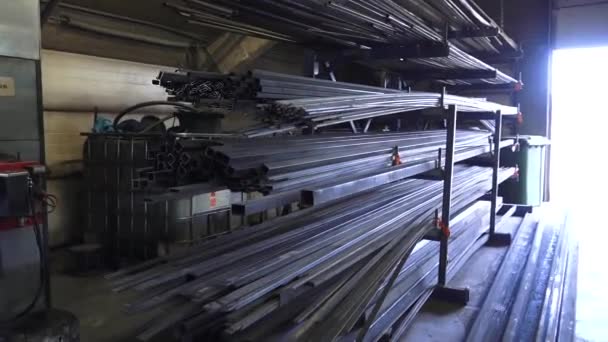 2024年3月17日 ラトビアのヴィラ 正方形の管および棒を含む金属のプロフィールの品揃え 開いたドアからの明るいライトが付いている産業倉庫で棚に貯えられる — ストック動画