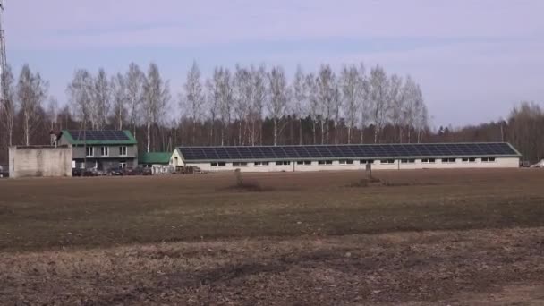 拉脱维亚瓦尔米耶拉 2024年3月17日 农村景观 其建筑顶部是太阳能电池板 而更大的建筑则是太阳能电池板阵列 四周是树木 — 图库视频影像