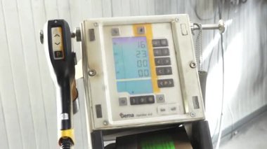 Valmiera, Letonya - 17 Mart 2024 Dijital ekran, düğmeler ve boya sprey tabancası olan bir endüstriyel makinenin kontrol paneli.
