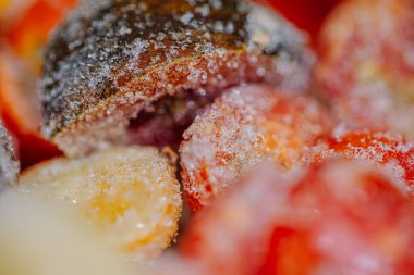 Buzla kaplı, dilimlenmiş domateslerin yakın çekimleri buzlu dokularını ve canlı kırmızı rengini ortaya çıkarıyor..