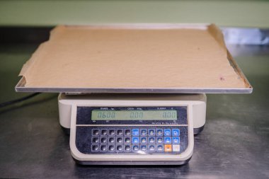 Üzerinde boş bir tepsi bulunan dijital bir ölçek yiyecek hazırlama alanında 0.600 kg ağırlığı gösterir..