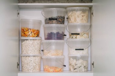 A pantry shelf with clear containers of various freeze-dried fruits and snacks. clipart