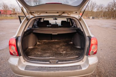 Valmiera, Latvia - March 17, 2024 - View of an open trunk of a silver station wagon, revealing a spacious boot with a protective mat, parked in an empty lot. clipart
