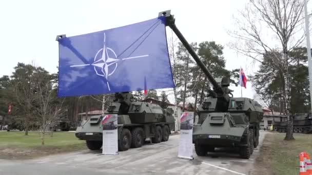 屋外イベントで軍用車両間のクレーンによって提起された大規模なNato旗 — ストック動画