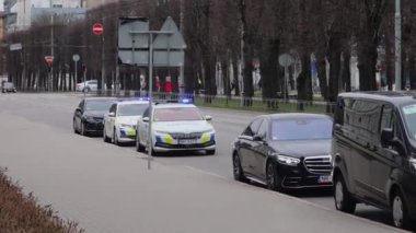 Riga, Letonya - 4 Nisan 2024-A konvoyu polis arabaları ve siyah resmi araçlarla şehir caddesinde, polis ışıkları etkinleştirildi.