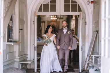 Valmiera, Letonya - 28 Temmuz 2024 Evlendikten sonra ışıl ışıl bir gelin ve damat bir kilisenin kapısından içeri girdi..