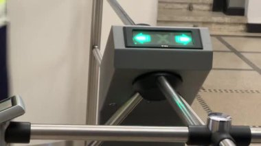 Riga, Letonya - 4 Nisan 2024 - Sarı yelekli bulanık bir figür yeşil ok göstergeleriyle bir erişim kontrol turnikesinden geçiyor.