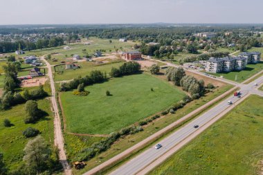 Valmiera, Letonya - 7 Ağustos 2023 - Evleri, yeşil tarlaları, yolları ve ağaçları olan bir banliyö manzarası.