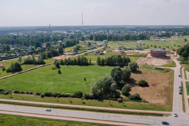 Valmiera, Letonya - 7 Ağustos 2023 - Evleri, yeşil tarlaları, yolları ve ağaçları olan bir banliyö manzarası.