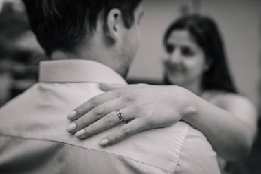 Adamın omzunda nişan yüzüğü olan bir kadının eli. Arka planda odakları bozuk bir kadın..