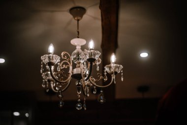 Valmiera, Letonya - 10 Ağustos 2023 - loş aydınlatılmış bir odada mum ve kristal süslemelerle süslü bir avize.