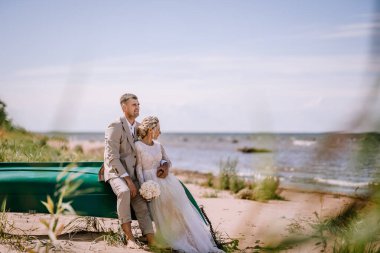Valmiera, Latvia - August 10, 2023 - Bride and groom sitting on a boat at the beach clipart