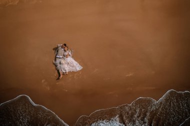 Valmiera, Letonya - 10 Ağustos 2023 - Kumlu bir kumsalda kucaklaşan bir çiftin hava manzarası.