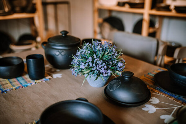 Валмиера, Латвия - 10 августа 2023 года - Керамическая керамика и букет синих цветов на ржавом деревянном столе.