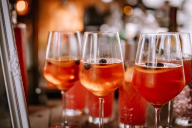 Valmiera, Letonya - 10 Ağustos 2023 - Bar tezgahında yabanmersinli Aperol Spritz kokteylleri, sıcak ortam.