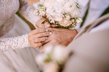 Valmiera, Letonya - 10 Ağustos 2023 Gelin ve damat el ele tutuşuyor, yüzükler ve buketler sergileniyor.