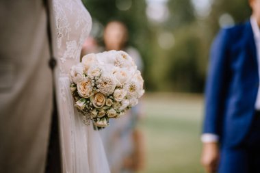 Valmiera, Letonya - 10 Ağustos 2023 - Arka planda bulanık damat ve sağdıç demeti tutan bir gelinin yakın çekimi.