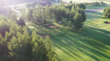 Valmiera, Letonya - 12 Ağustos 2023 - Güneşli golf sahası Ağaçların arasında kum sığınakları ve uzun gölgeler.