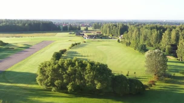 2023年8月12日 ラトビアのラトビア 緑豊かなフェアウェイとクラブハウスに近づくゴルフコース上のドローン飛行 — ストック動画