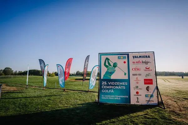 Valmiera, Letonya - 12 Ağustos 2023 - Açık bir golf sahasında golf etkinliği tabelası ve sponsor pankartları.
