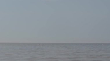 Uçsuz bucaksız sakin gökyüzünün altında uzak bir yüzücü.