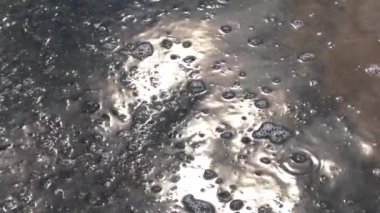 Güneş ışığı görünür kum ve kabarcıklarla suya yansıyor..