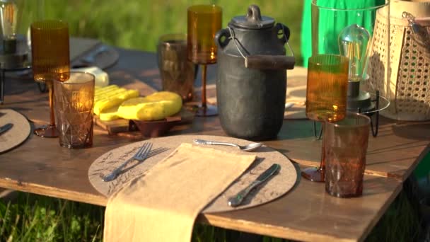 带有琥珀色眼镜的野餐桌 餐盘上的餐具 阳光下的黑色茶壶 — 图库视频影像