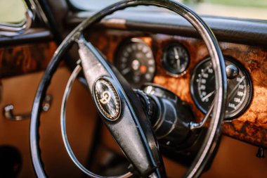 Valmiera, Letonya - 19 Ağustos 2023 - Klasik bir arabanın direksiyon ve gösterge panelinin yakın çekimi, karmaşık ahşap paneller ve klasik tasarım elementleri.