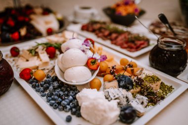 Valmiera, Letonya - 19 Ağustos 2023 - Bir çeşit peynir, taze meyve ve çeşitli süslerle süslenmiş bir açık büfe masası.