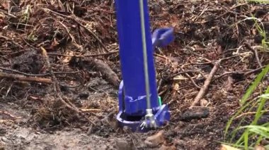 Yeniden ağaçlandırma çalışmaları sırasında, doğal atıklarla çevrili, toprağa yerleştirilmiş mavi bir ağaç dikme aracının yakın çekimi..