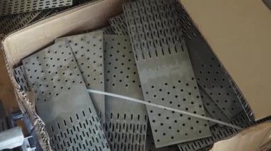 Balvi, Letonya - 25 Mayıs 2024 - Bir sanayi ortamında inşaat ve ahşap işçiliği projelerinde kullanılan metal delikli plakalarla dolu bir kutu.
