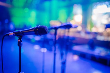 Valmiera, Letonya - 31 Mayıs 2024 - Bulanık arka plan ışıklarıyla loş, renkli sahne ayarlı bir tezgahta bir mikrofonun yakın çekimi.