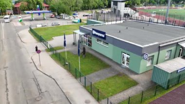 Cesis, Letonya, 29 Mayıs 2024 - Güneşli bir günde çevrede yolları ve arabaları olan bir benzin istasyonu ve spor sahasının yanındaki Husqvarna mağazasının havadan görünüşü.