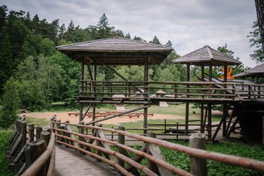 Dobele, Letonya - 7 Haziran 2024 - Ormandaki bir park alanındaki yürüyüş yolları ve arka planda banklar ve yeşillikler ile bağlı tahta gözlem güverteleri.