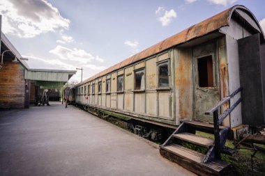 Dobele, Letonya - 7 Haziran 2024 - Güneşli bir günde eski bir istasyonda terk edilmiş bir tren vagonu çürümenin ve nostaljinin özünü yakalıyor..