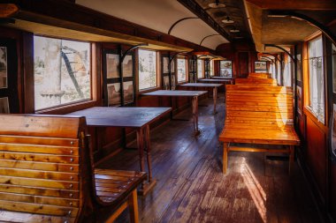 Dobele, Letonya - 7 Haziran 2024 - Duvarlarında antika fotoğraflar bulunan ahşap bankları ve masaları olan eski moda bir tren vagonu..