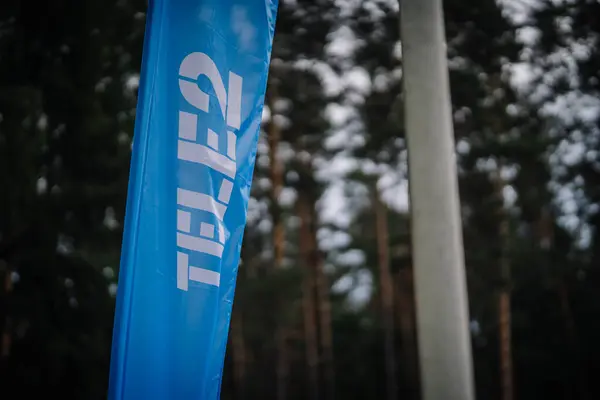 Dobele, Letonya - 7 Haziran 2024 - Bulanık bir orman arka planına karşı mavi bir Tele2 afişi, açıkça şirketin logosunu gösteriyor. Boşluğu kopyala.