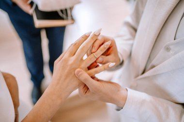 Valmiera, Letonya - 9 Eylül 2023 - Damadın nikah töreni sırasında gelinin parmağına yüzük takması, ayrıntılı manikür ve yüzükler sergilenmesi,.