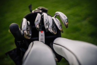 Sigulda, Letonya - 10 Eylül 2023 - 5 'ten 9' a kadar numaralandırılmış demirler ve yeşil çimen arka planına kurulmuş golf sopalarının yakın çekimi.