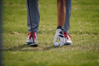 Sigulda, Letonya - 10 Eylül 2023 - Golf sopası ve kırmızı ayakkabılı bir eldiven ve akıllı saat takan bir golfçünün eline yakın çekim.