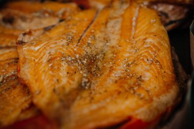 Limbazi, Letonya, 29 Haziran 2024 - Görünür doku ve baharatlı tütsülenmiş somon filetolarının yakın çekimi. Altın-kahverengi balık servis edilmeye hazır..