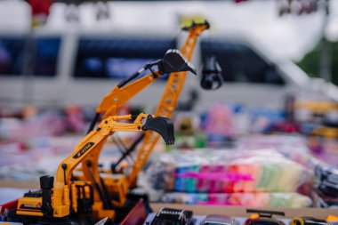 limbazi, Letonya, 29 Haziran 2024 - Kazı makinesi ve vinç de dahil olmak üzere oyuncak inşaat araçlarının yakın çekimi, açık hava pazarındaki bir masada sergilendi. Arka planda diğer oyuncaklar görünür..